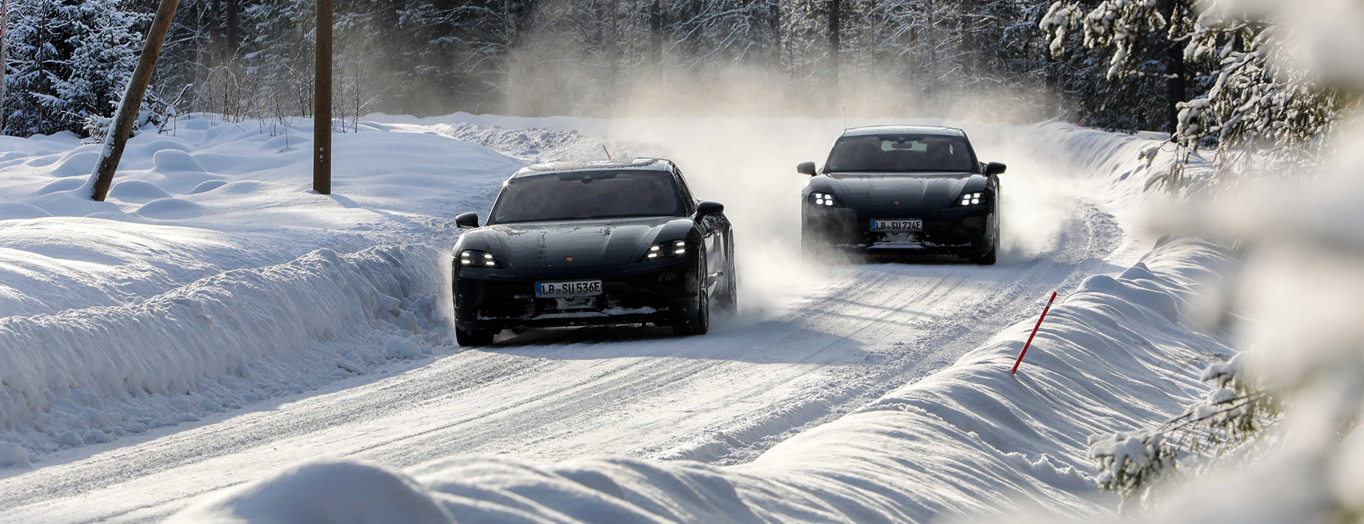 Two black Porsche Taycan cars in snow