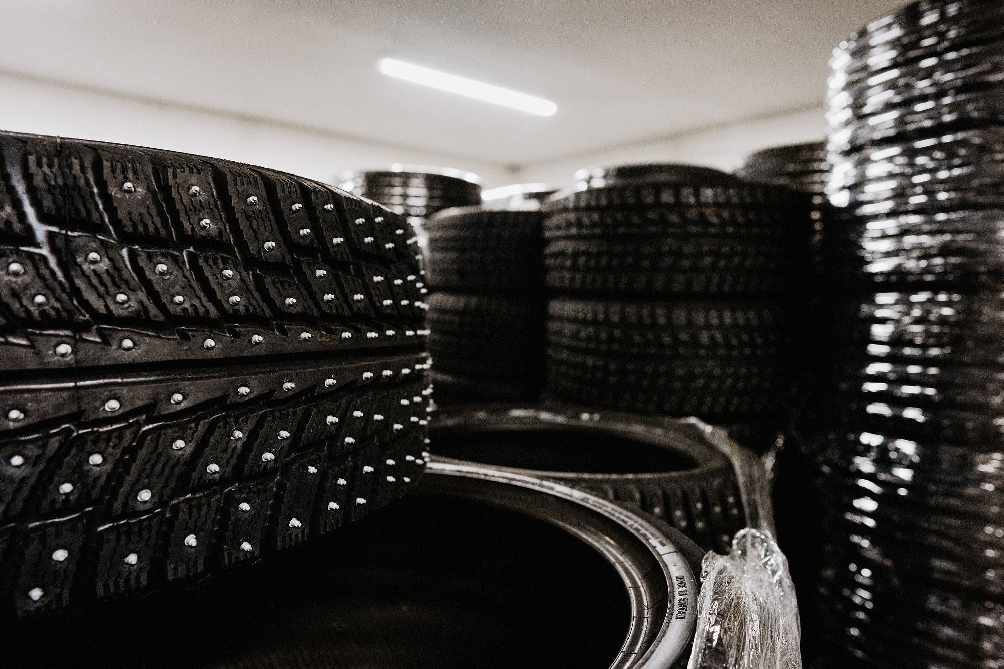 Studded car tyres stacked vertically in a lit room
