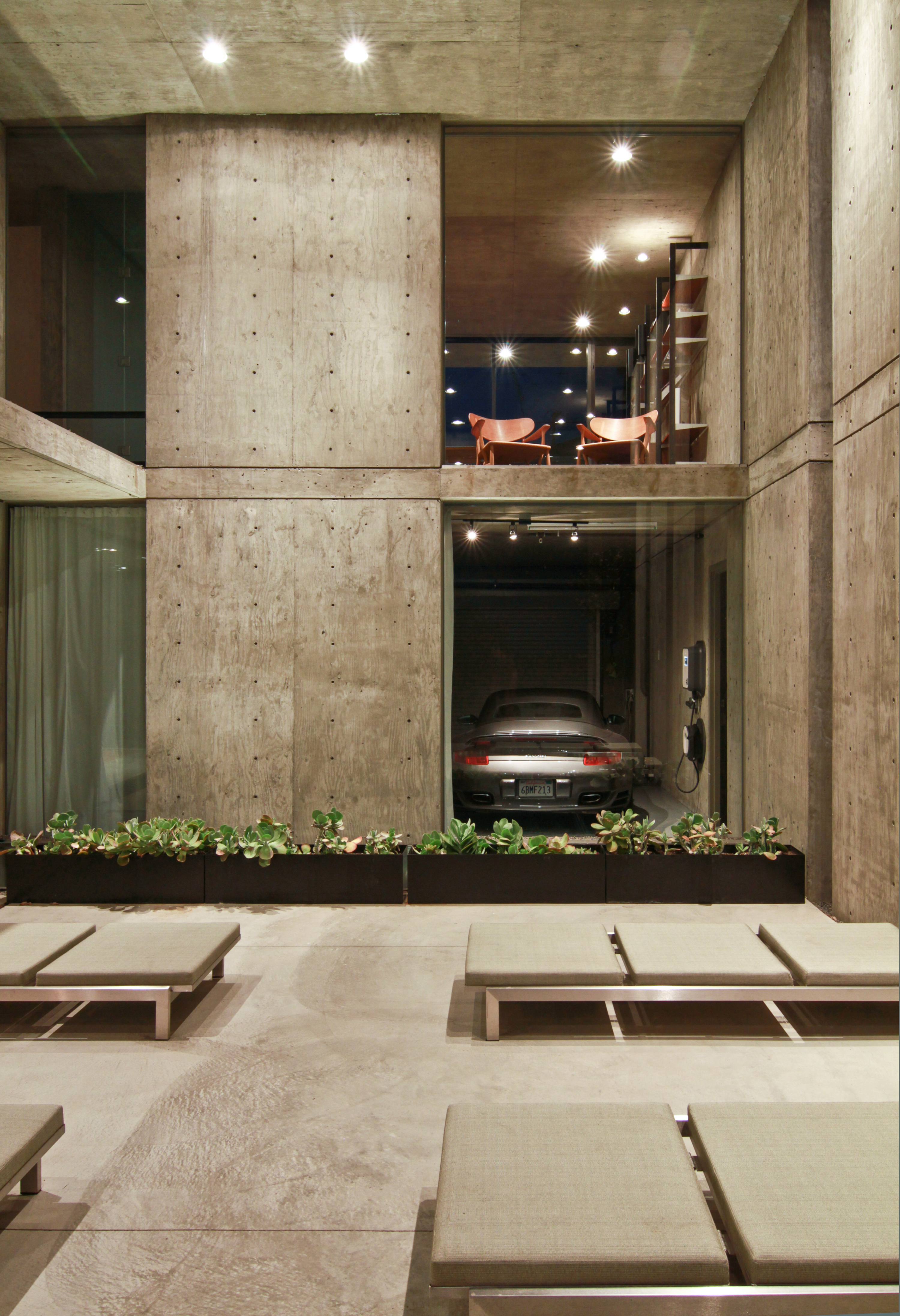 Porsche 911 behind glass window in concrete-constructed designer house