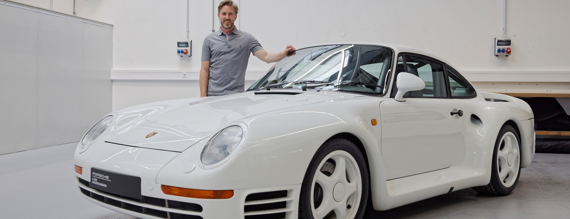 Nick Heidfeld standing behind white Porsche 959 S