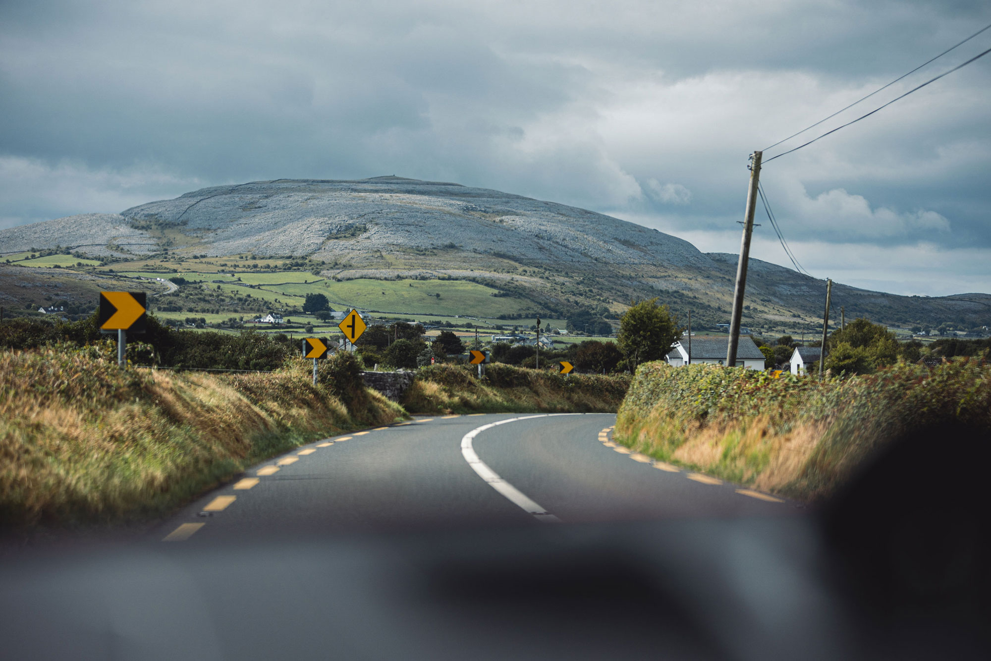 View of Irish country road from car, mountain in distance