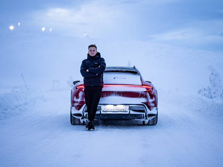 Man stands next to red Porsche Taycan in snowy scene