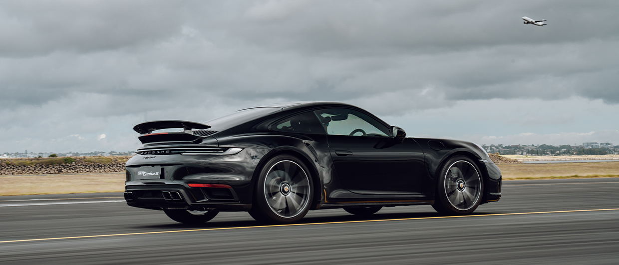 Black 911 Turbo S from rear side view on runway