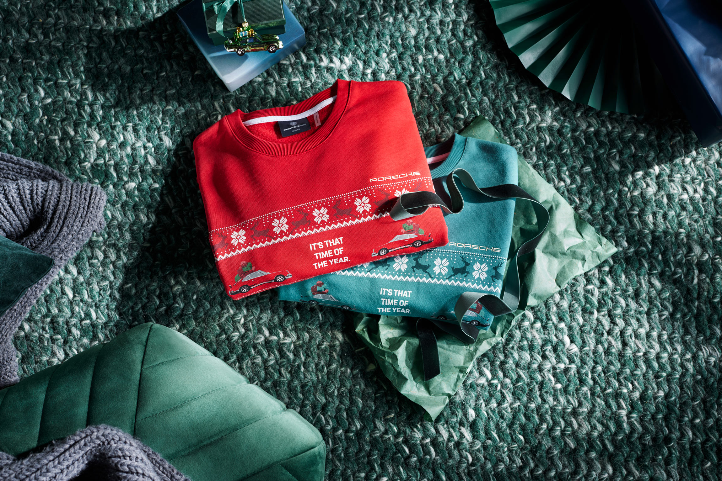Folded red Porsche Christmas jumper on top of green one