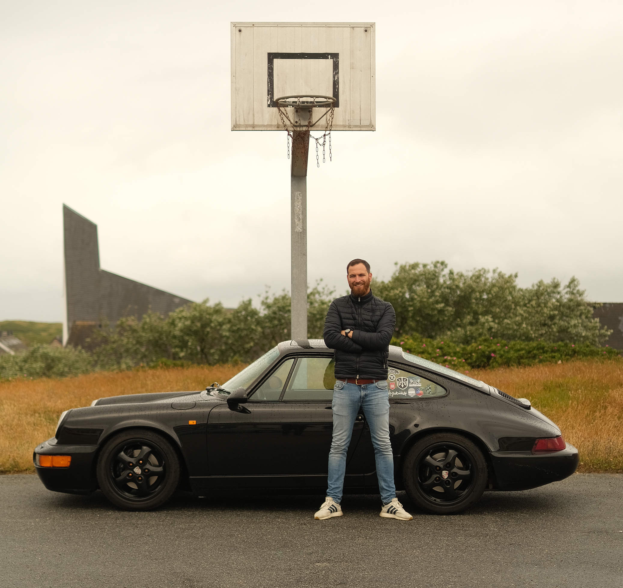 Man, arms folded, in front of a black Porsche 964
