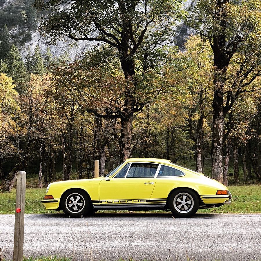 Side view of yellow 1973 Porsche 911 T in woods