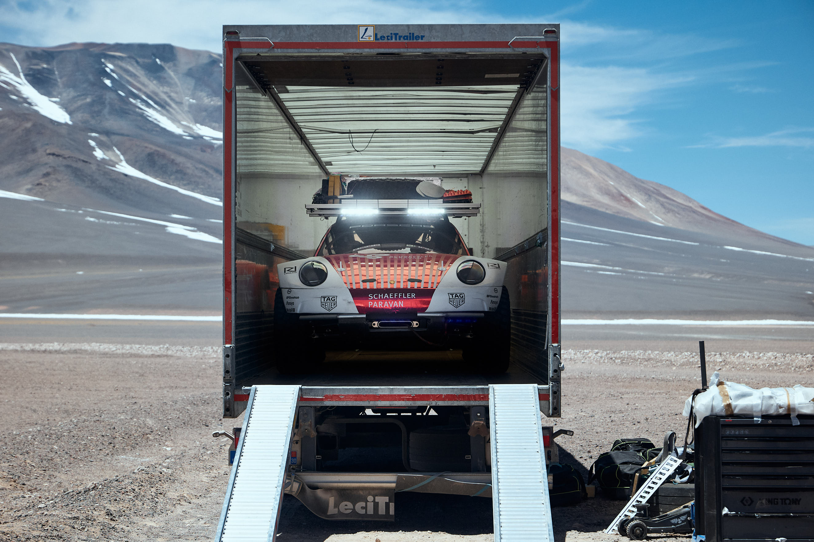 Off-road Porsche 911 facing out of truck, volcano in background