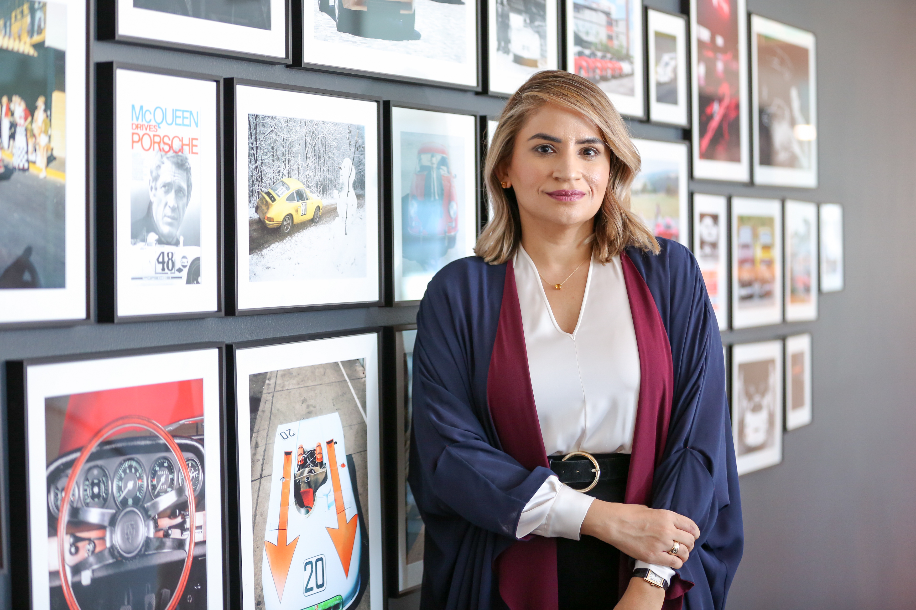 Woman stands in front of wall of automotive-related framed pictures