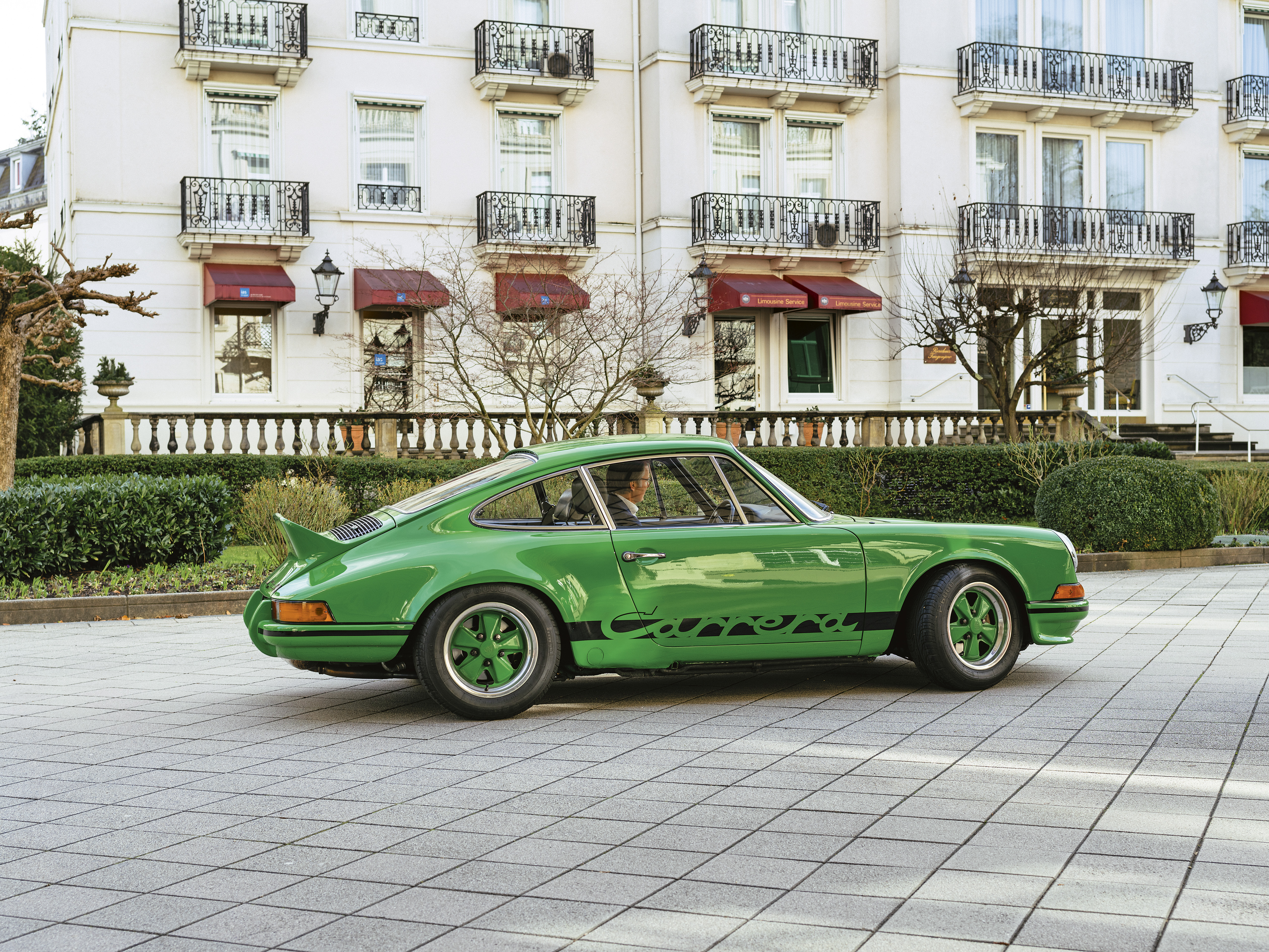 Green Porsche 911 Carrera RS 2.7 in front of apartments