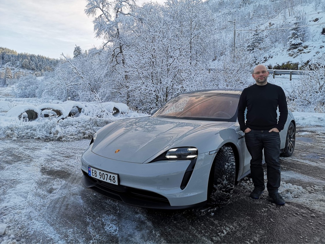 Man standing next to Taycan 4S, parked in winter landscape