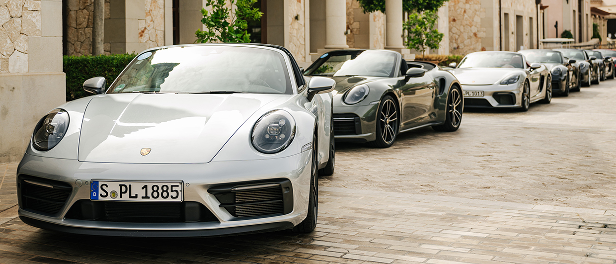 Line-up of Porsche 911 cars outside stone Mallorcan buildings