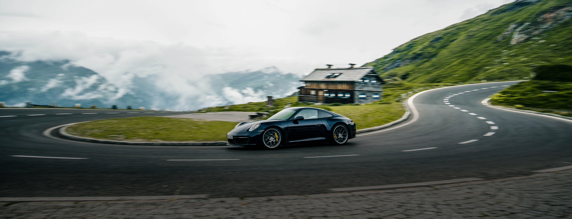 Black Porsche 911 on mountain switchback, on grey, cloudy day
