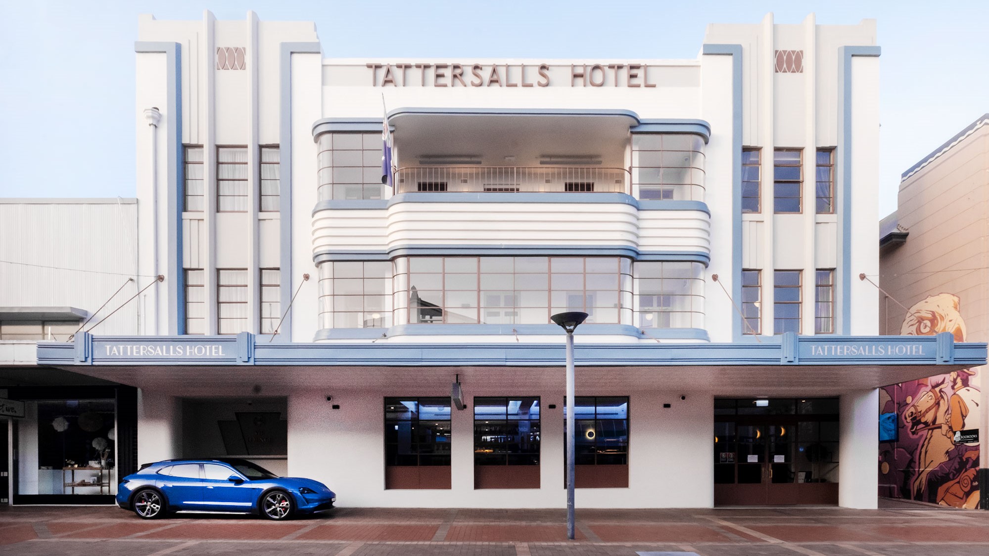 Porsche Taycan 4S Cross Turismo in front of Australian art deco hotel