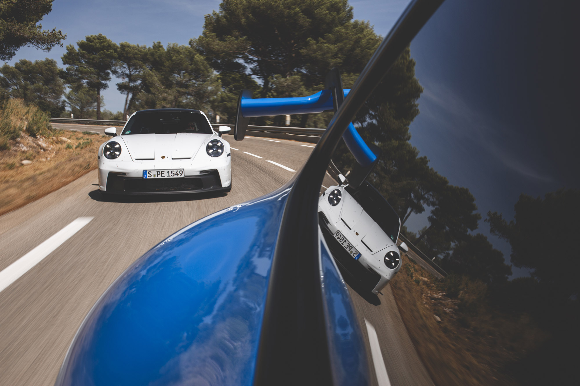 Two Porsche 911 GT3 cars driving on French hillside roads