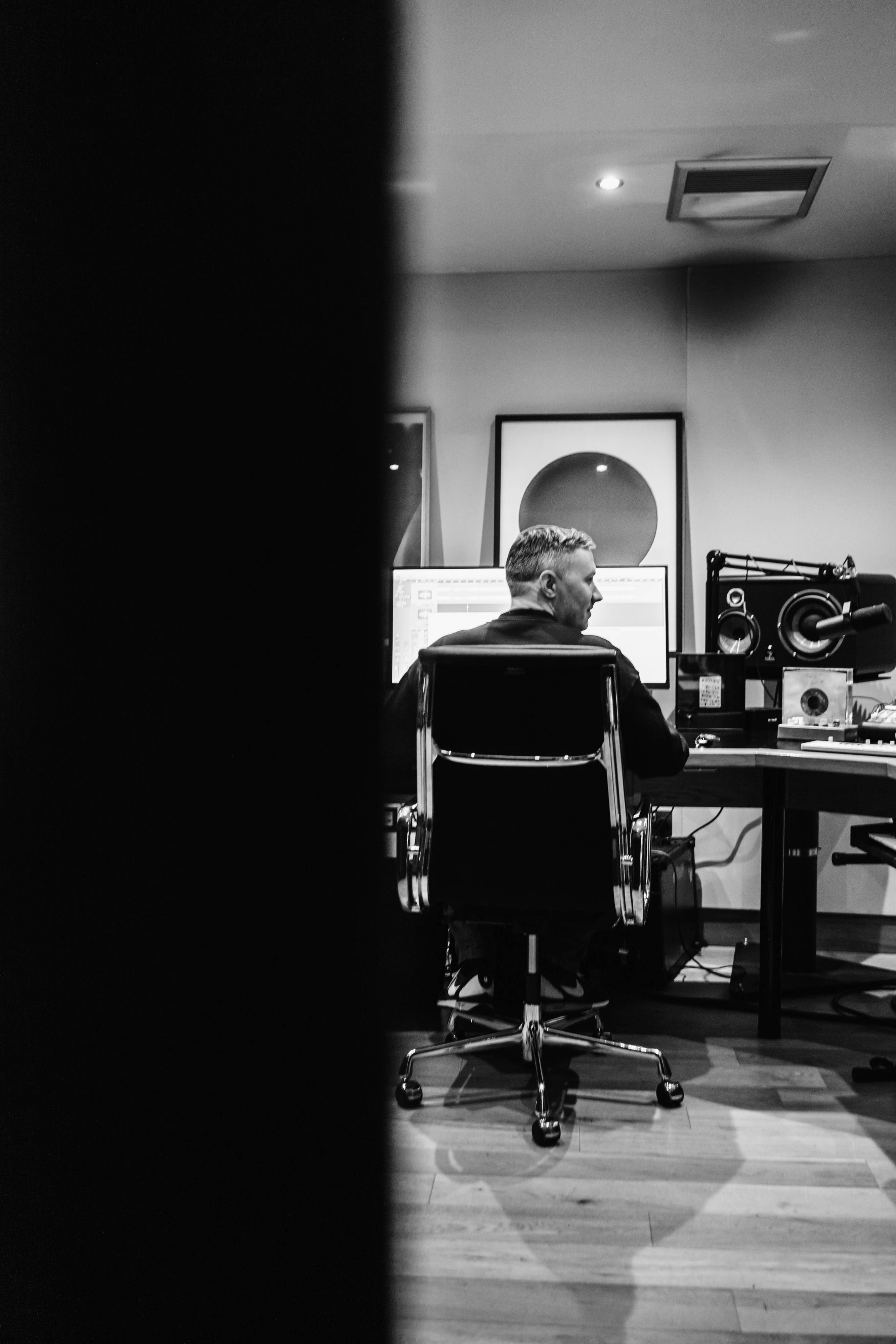 Monochrome image of Benji sat in studio shot from behind