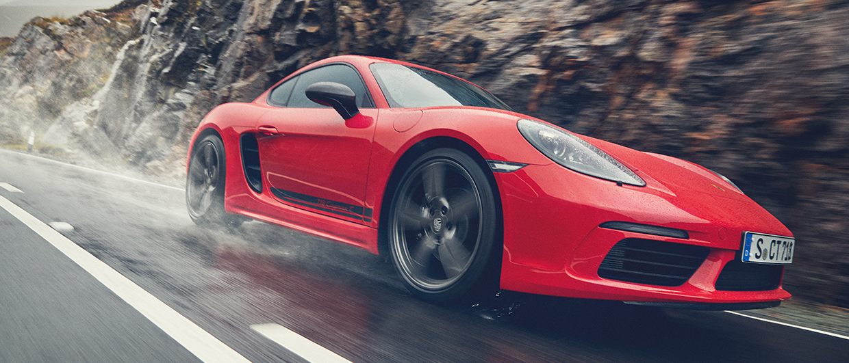 Red Porsche 718 Cayman T on wet road in Iceland
