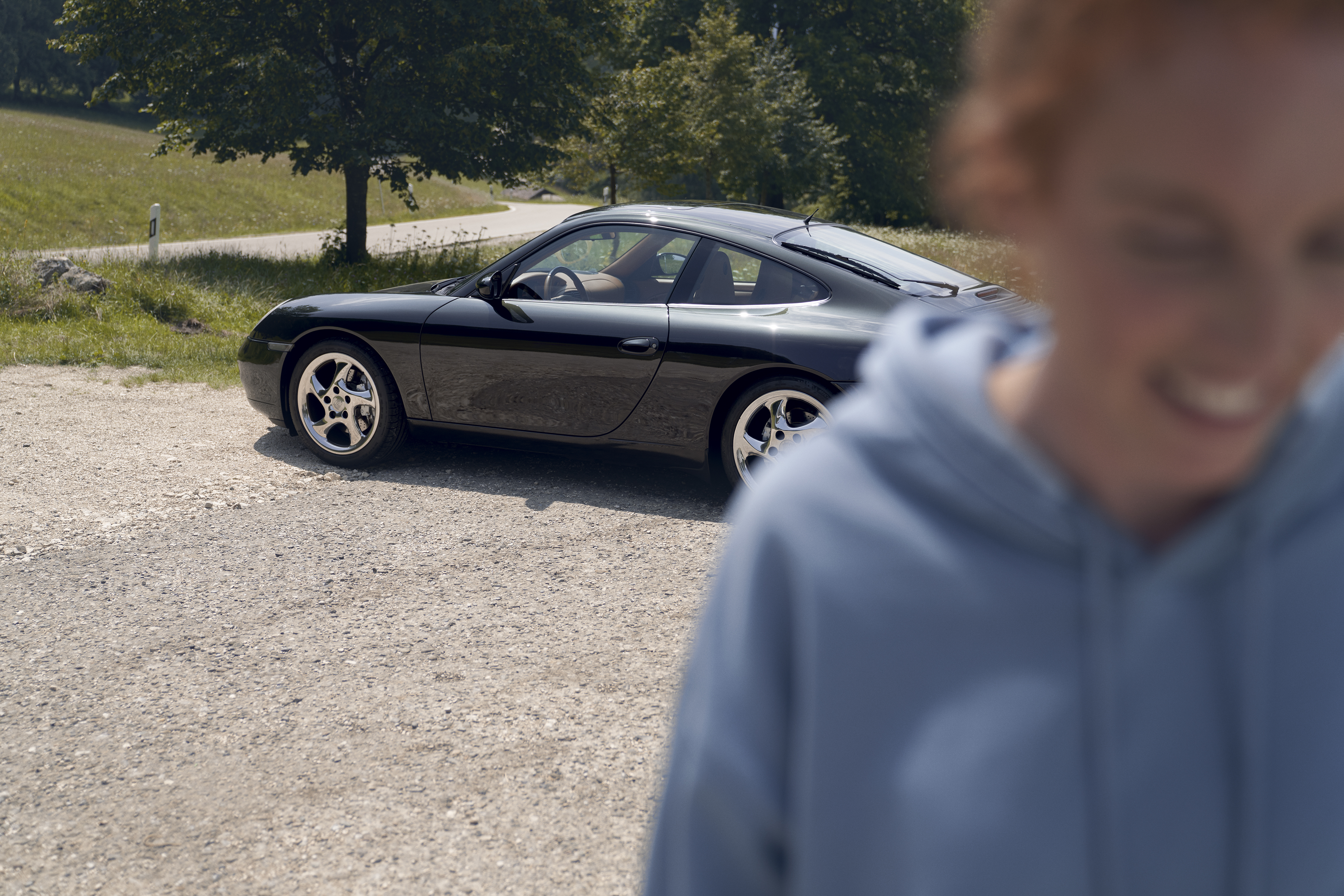 Dark blue 996 Carrera in sunlight, smiling woman in foreground