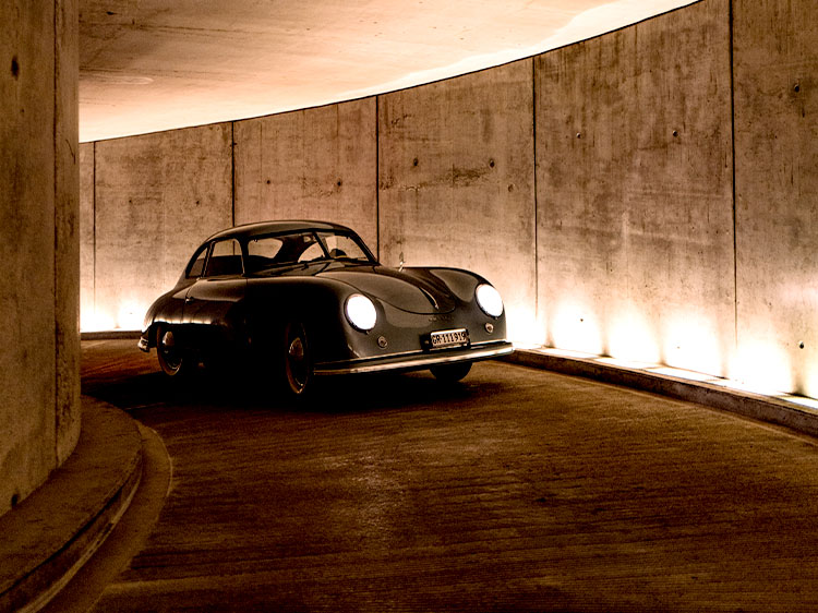 Porsche 356, headlights on, driving up underground car park ramp