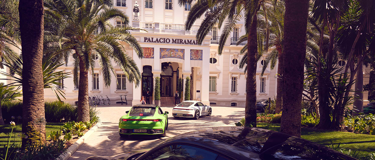 Green Porsche 911 is driving in front of the Miramar Hotel