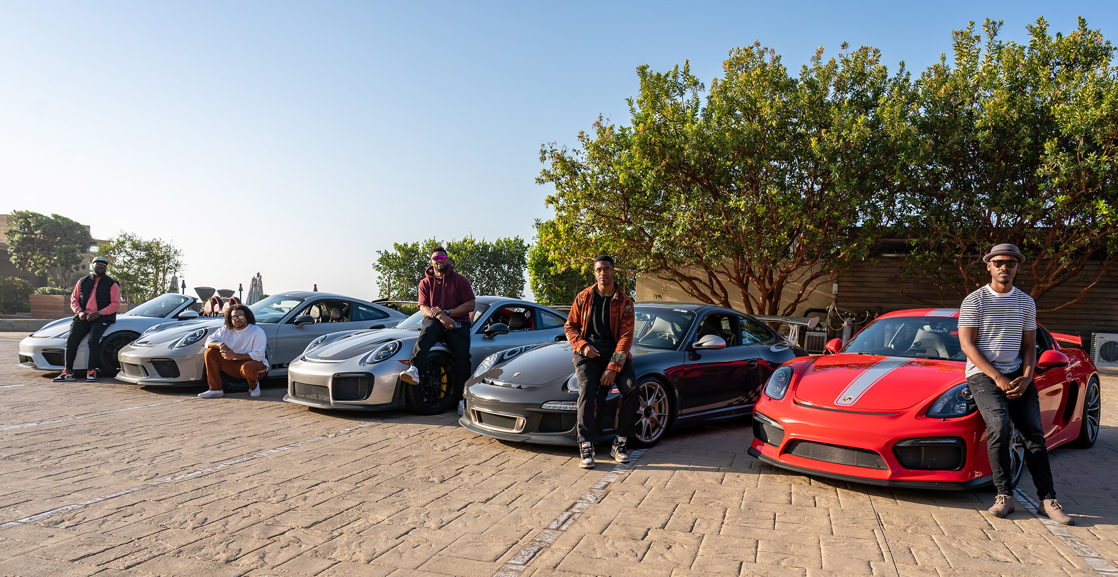 Five men standing beside five Porsche sports cars