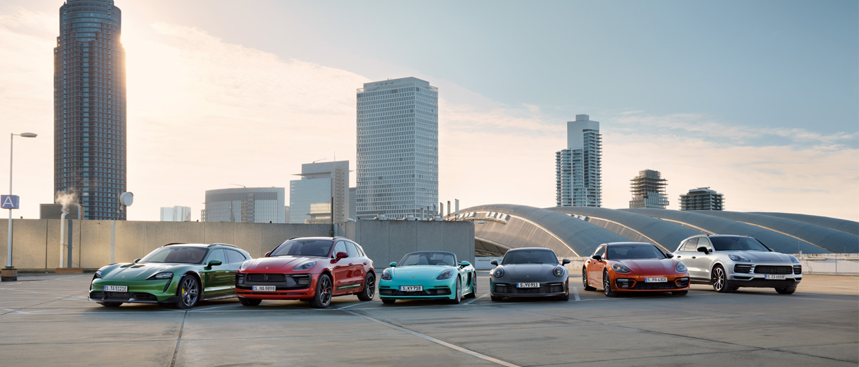 Seven Porsche models lined up against a city skyline