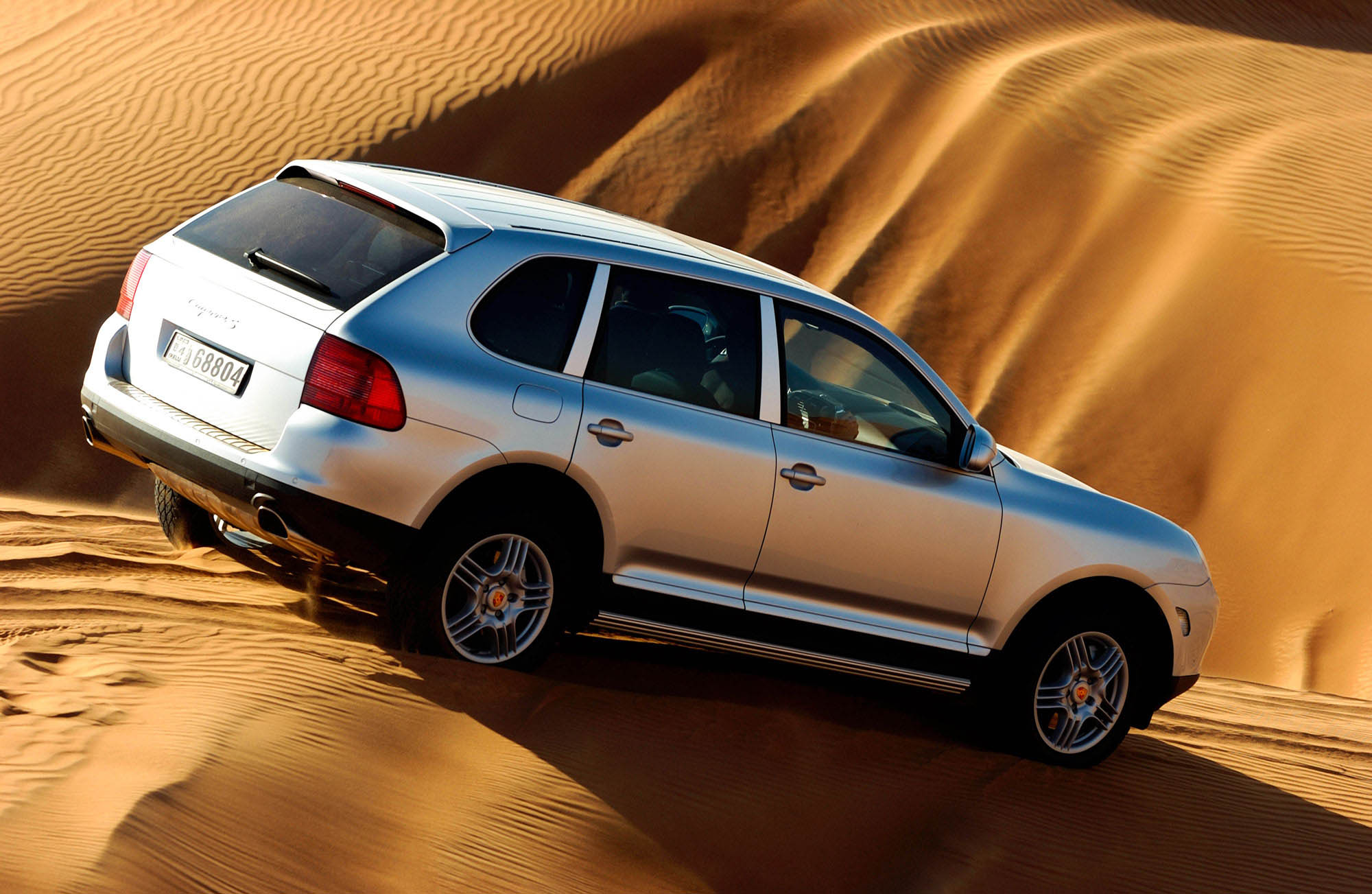 Porsche Cayenne pitches over the crest of a sand dune