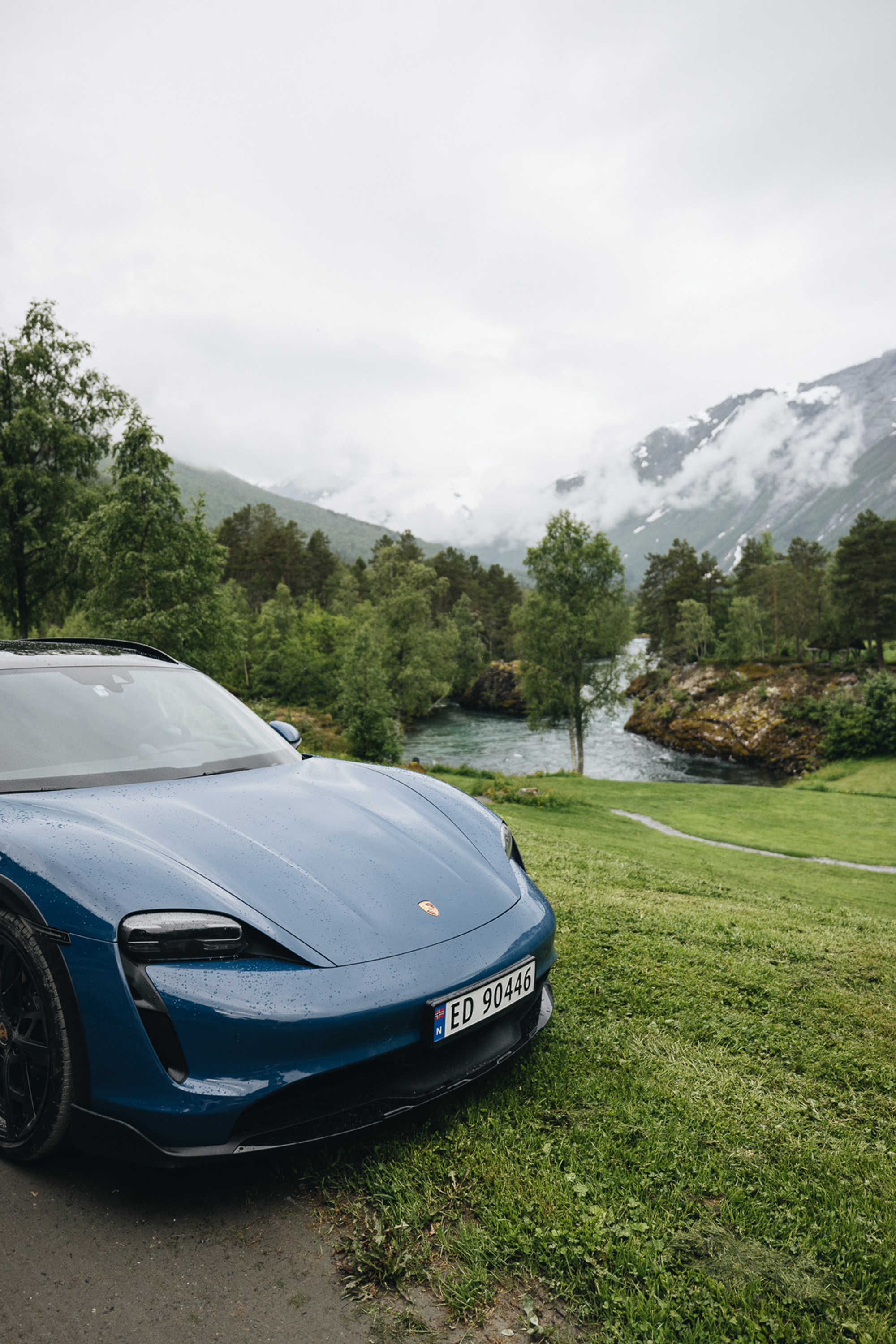Blue Porsche Taycan Cross Turismo in Norwegian fjord land scene