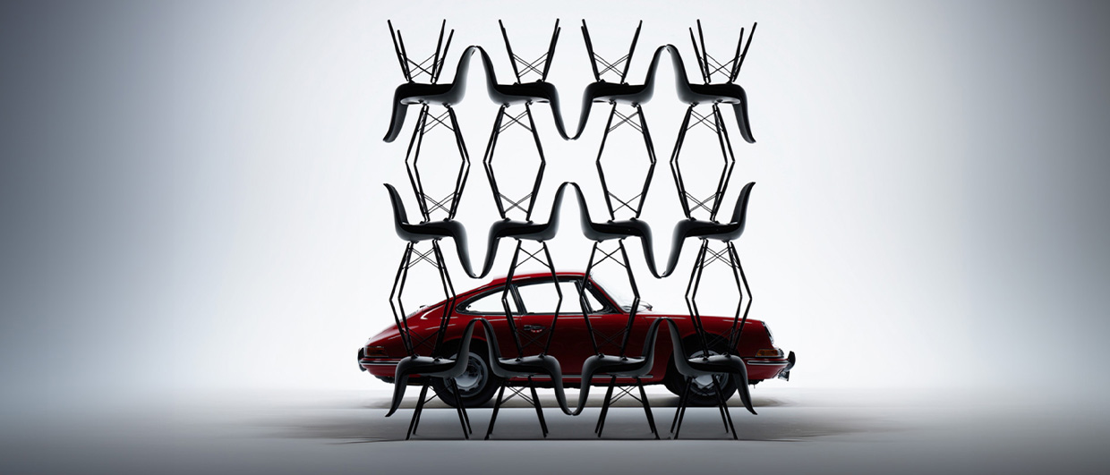 Red classic Porsche 911 behind stacked Vitra for Porsche chairs