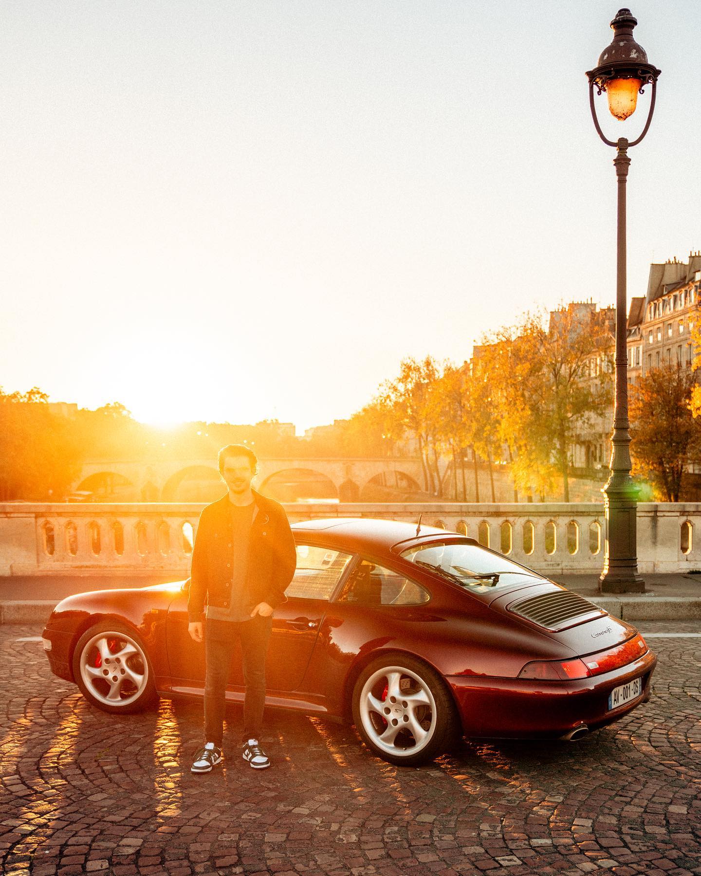 Man and Porsche 911 on Paris bridge at sunrise