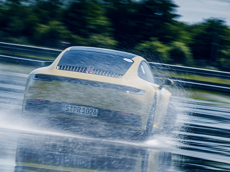 Rear view of yellow 911 drifting on wet track