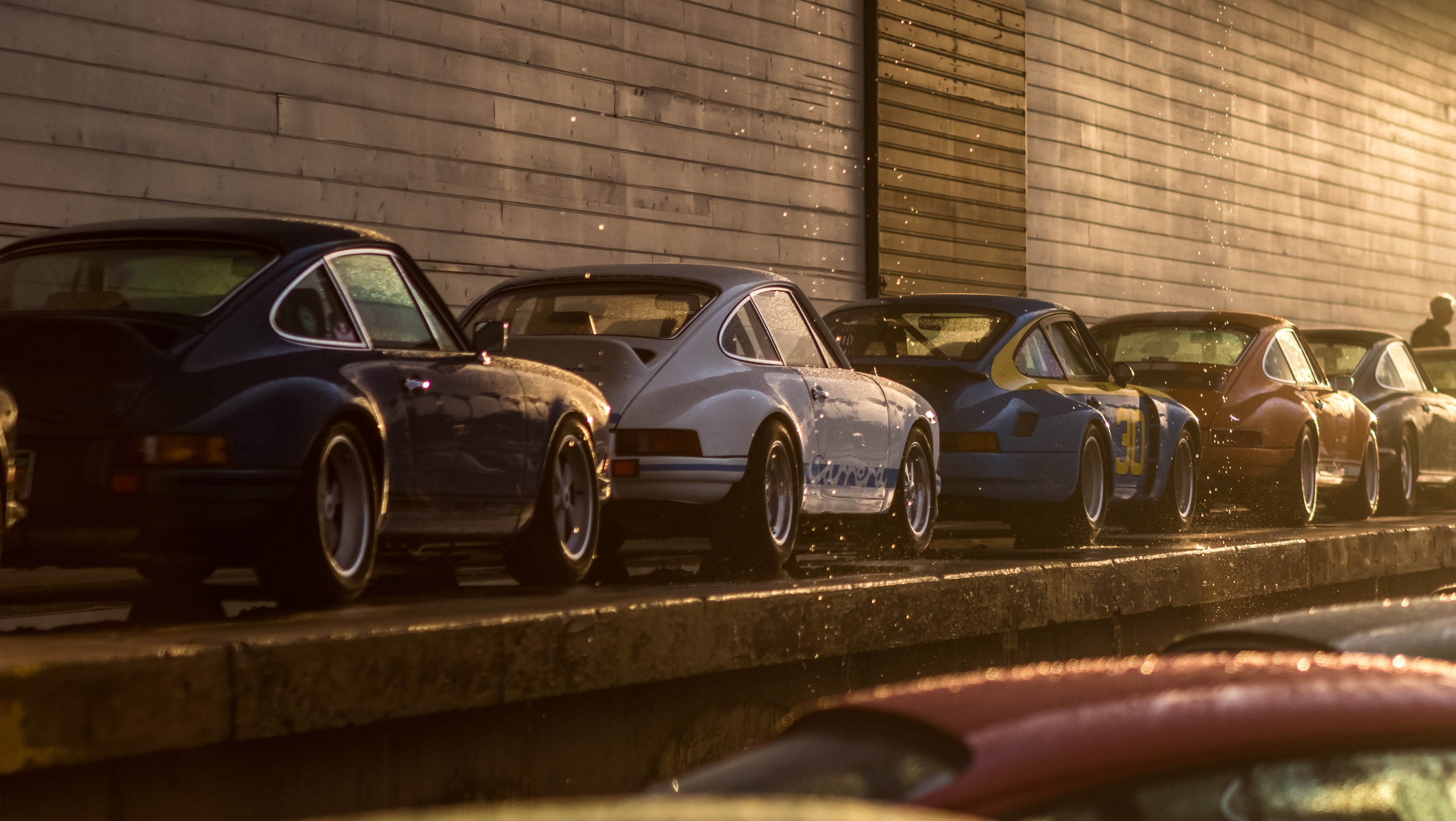 Line-up of classic Porsche sportscars in the rain
