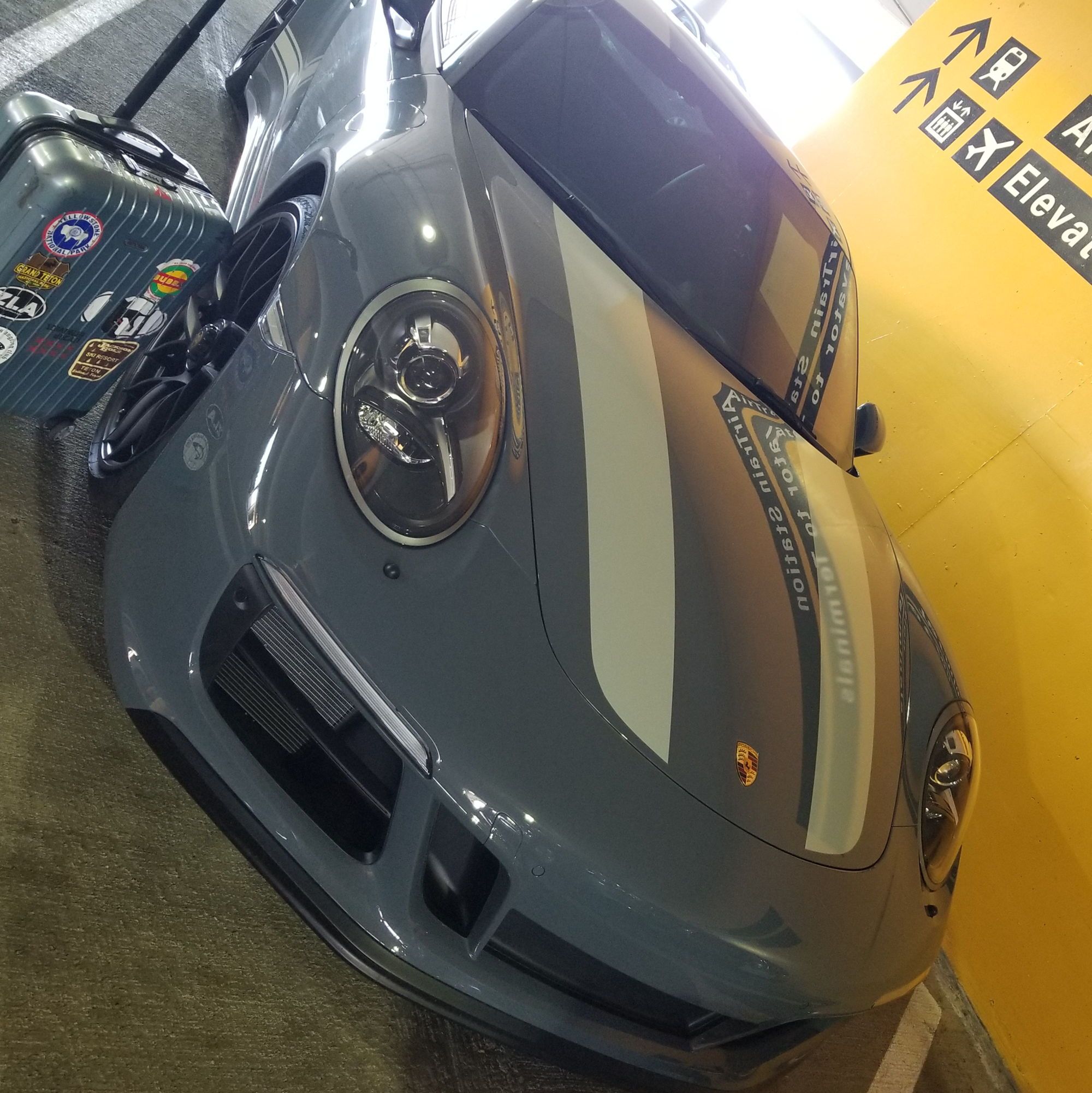 911 Carrera GTS at airport, suitcase beside it
