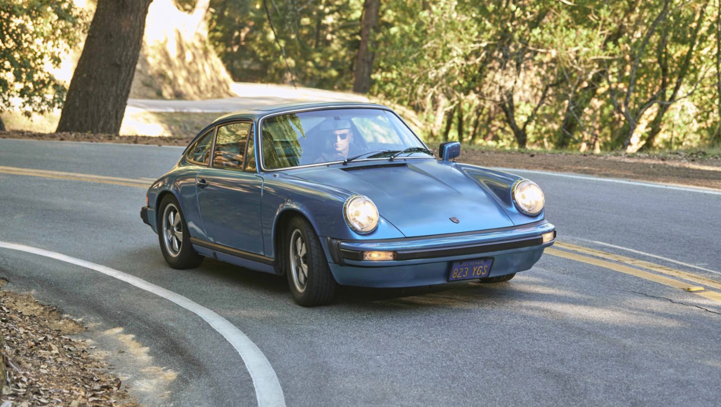 Porsche 911 S in Minerva Blue driving on tree-lined road