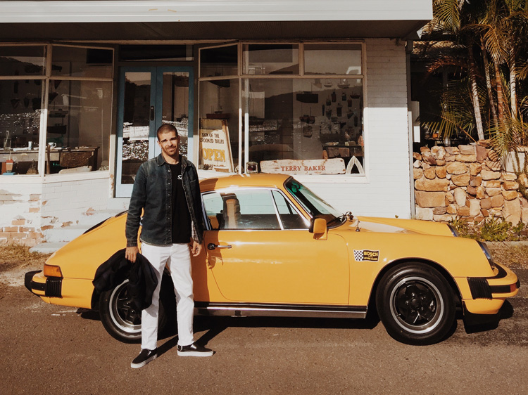 Man standing in front of a vintage yellow Porsche 911