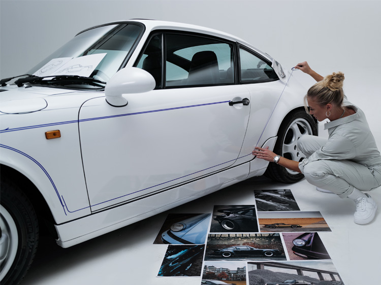 Artist marks reflective lines on white 964 Porsche with tape