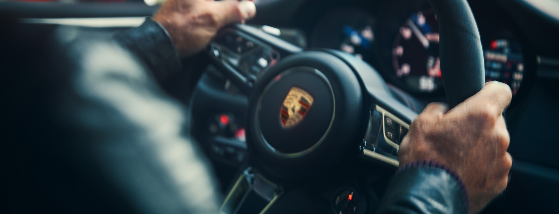 Man driving a Porsche, close-up of hands on steering wheel