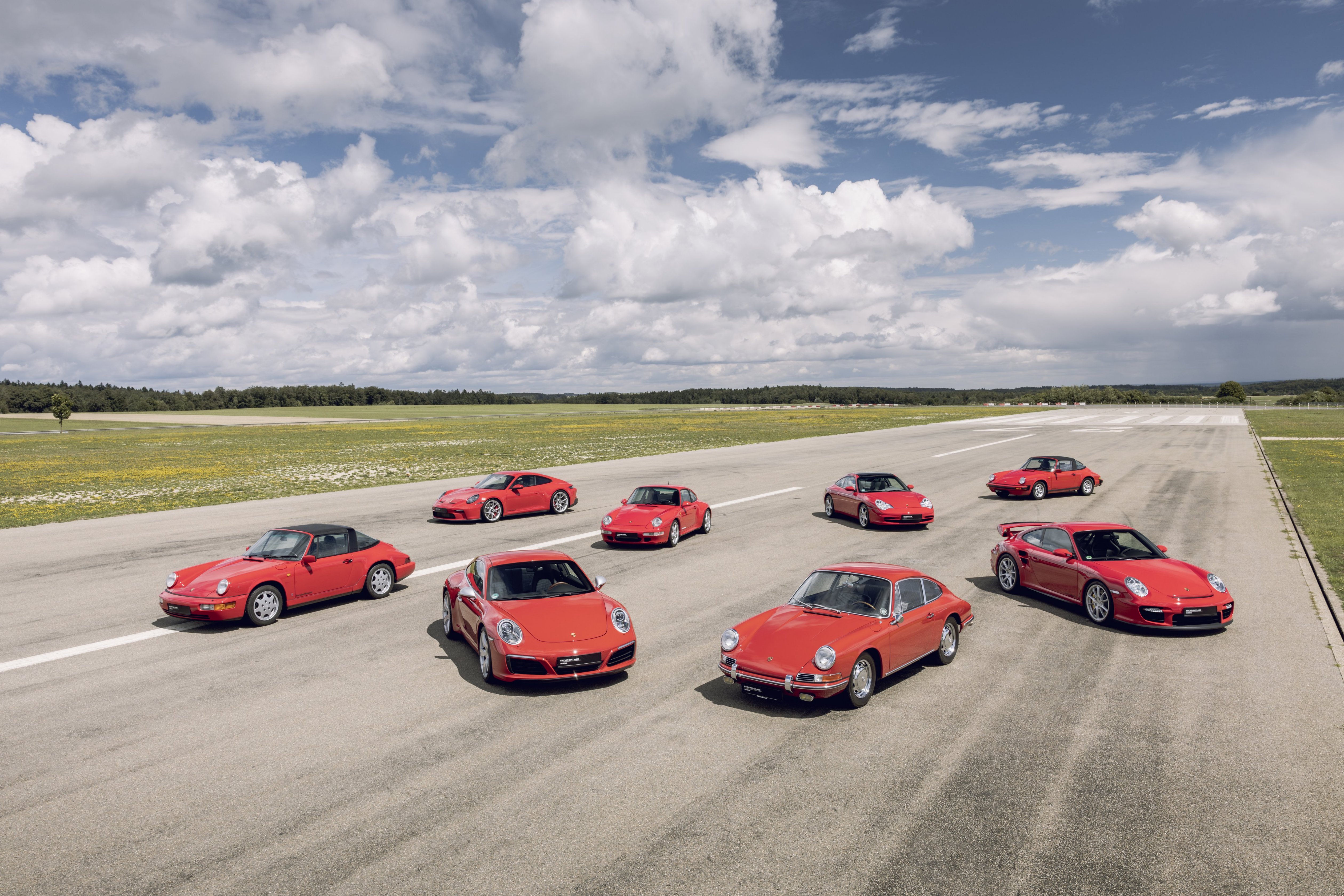 Eight red Porsche 911 cars on empty aircraft runway