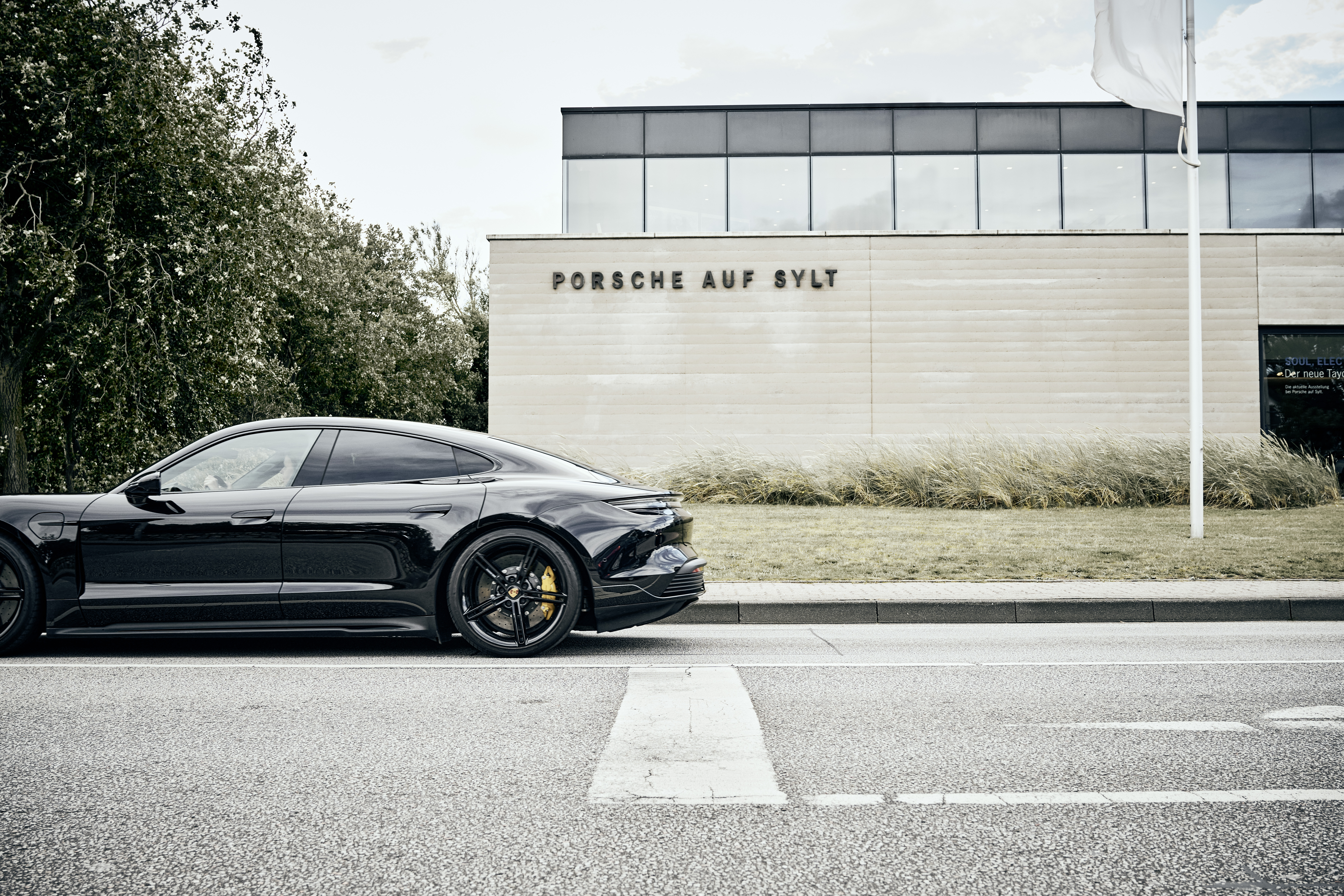 Black Taycan parked outside Porsche dealership in Sylt, Germany