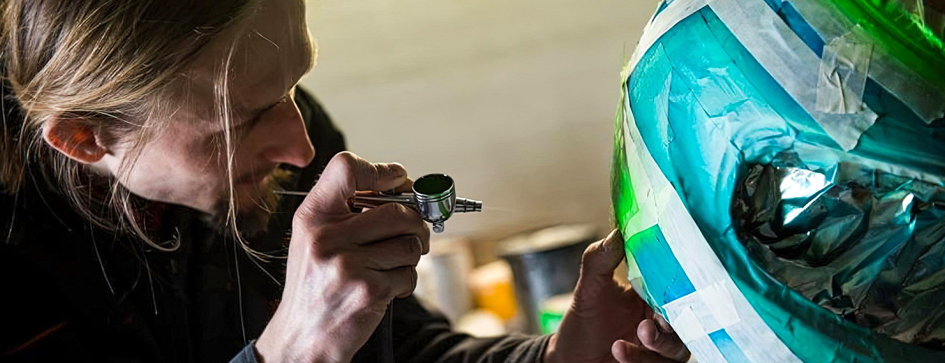 Designer sprays racing helmet with airbrush paint