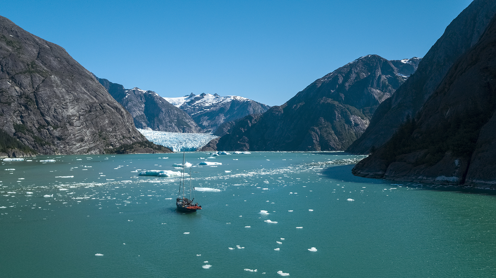 Panorama of sailing boat in bay, with mountains and glaciers