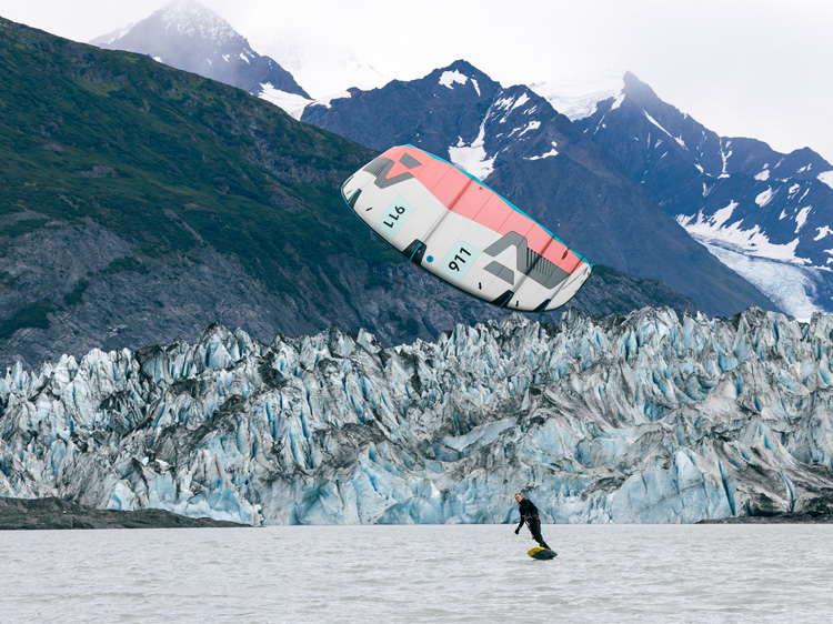 Kitesurfer on Alaskan waters, snowy mountains in background