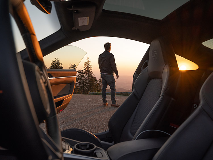 Man standing outside of Porsche looking into sunset