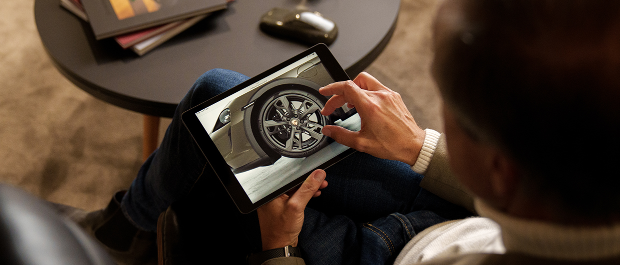 Close-up of man on iPad configuring a Porsche car