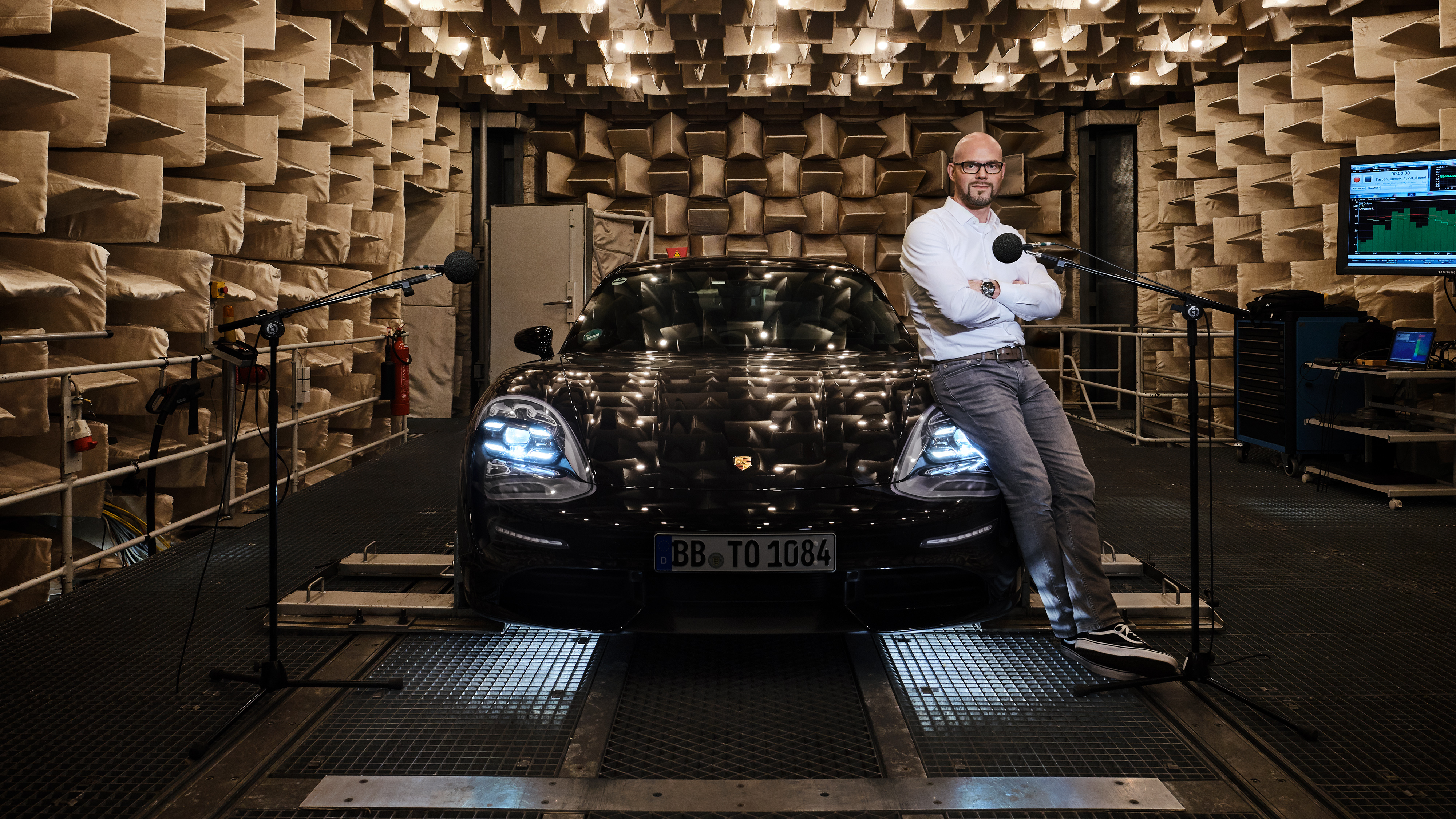 Man leans against Porsche Taycan in soundproof studio