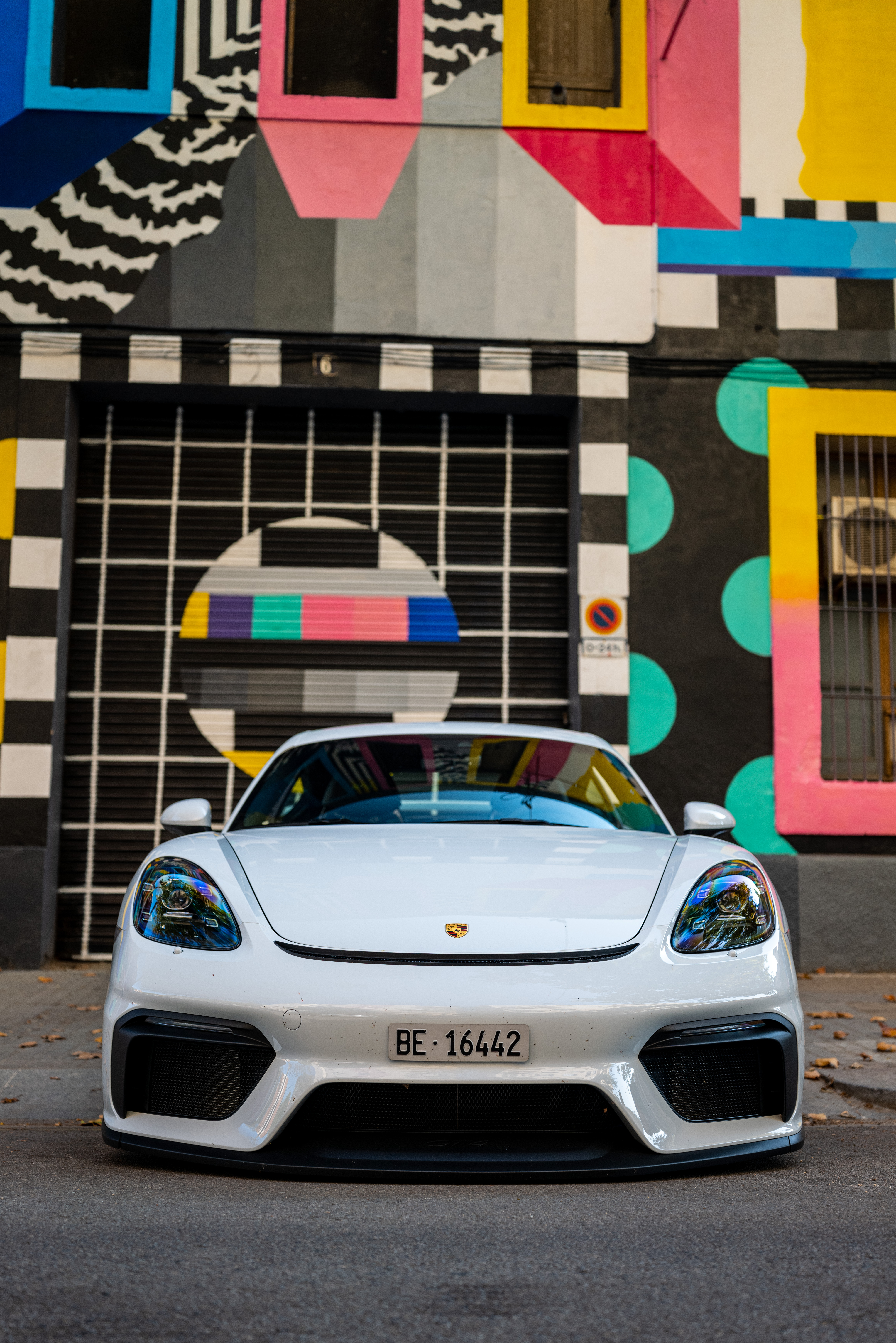 White Porsche 718 Cayman GT4 outside colourful modernist house
