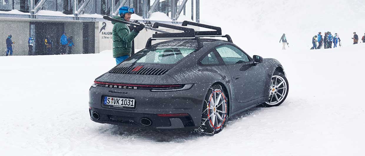 Grey Porsche 911 (type 992) with snow chains on tyres