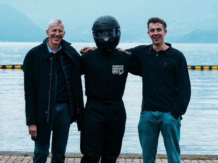 Three men posing in front of a lake and mountains