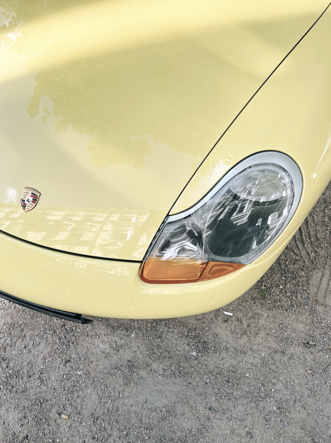Close-up of front headlamp of pastel yellow Porsche Boxster