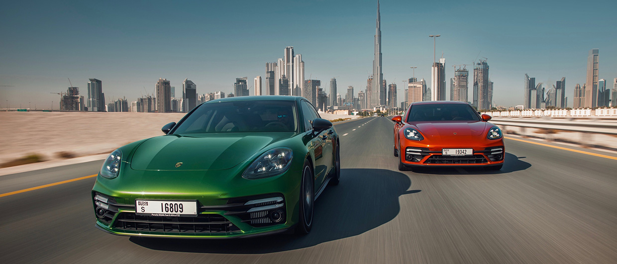 Green and red Panamera, side by side, Dubai skyline behind