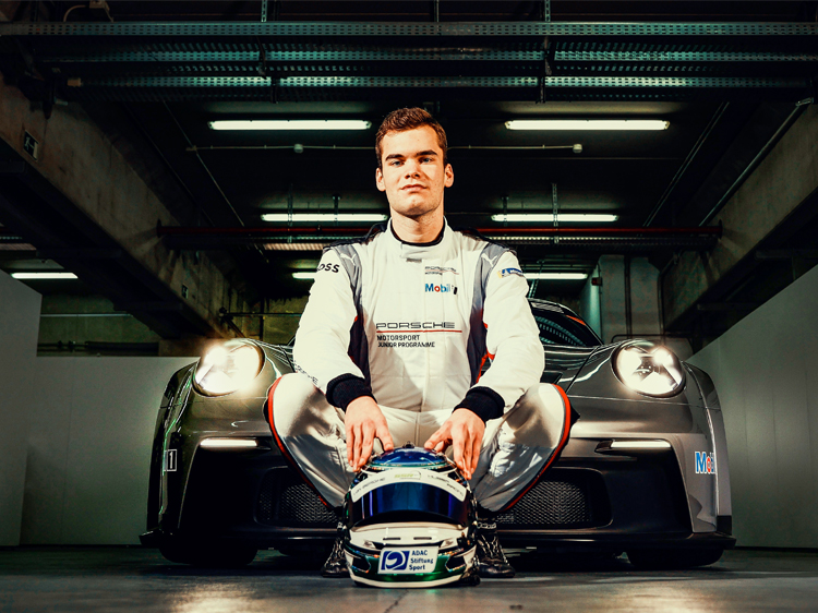 Laurin Heinrich in racing suit in front of Porsche racecar